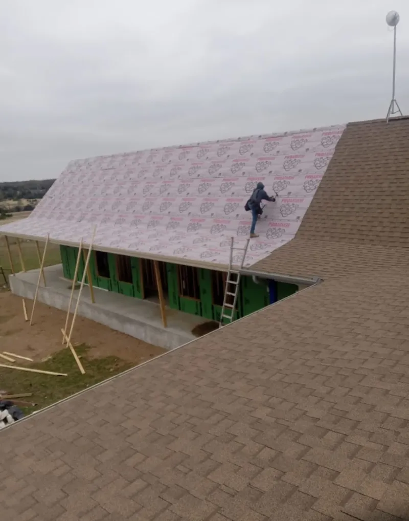 Worker preparing underlayment for a metal roof installation in Manorhaven